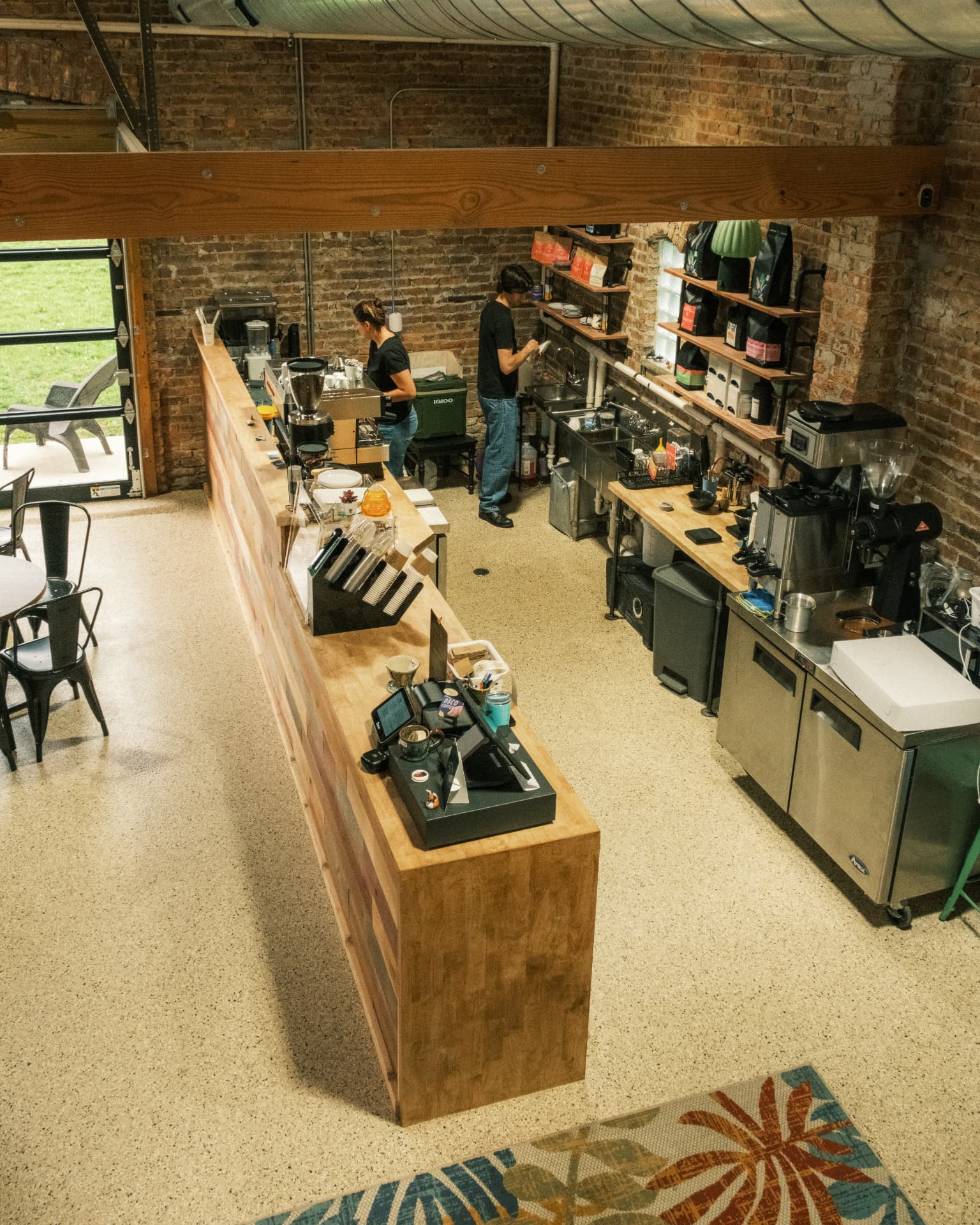 Two baristas working behind the long wooden DSCO Coffee counter
