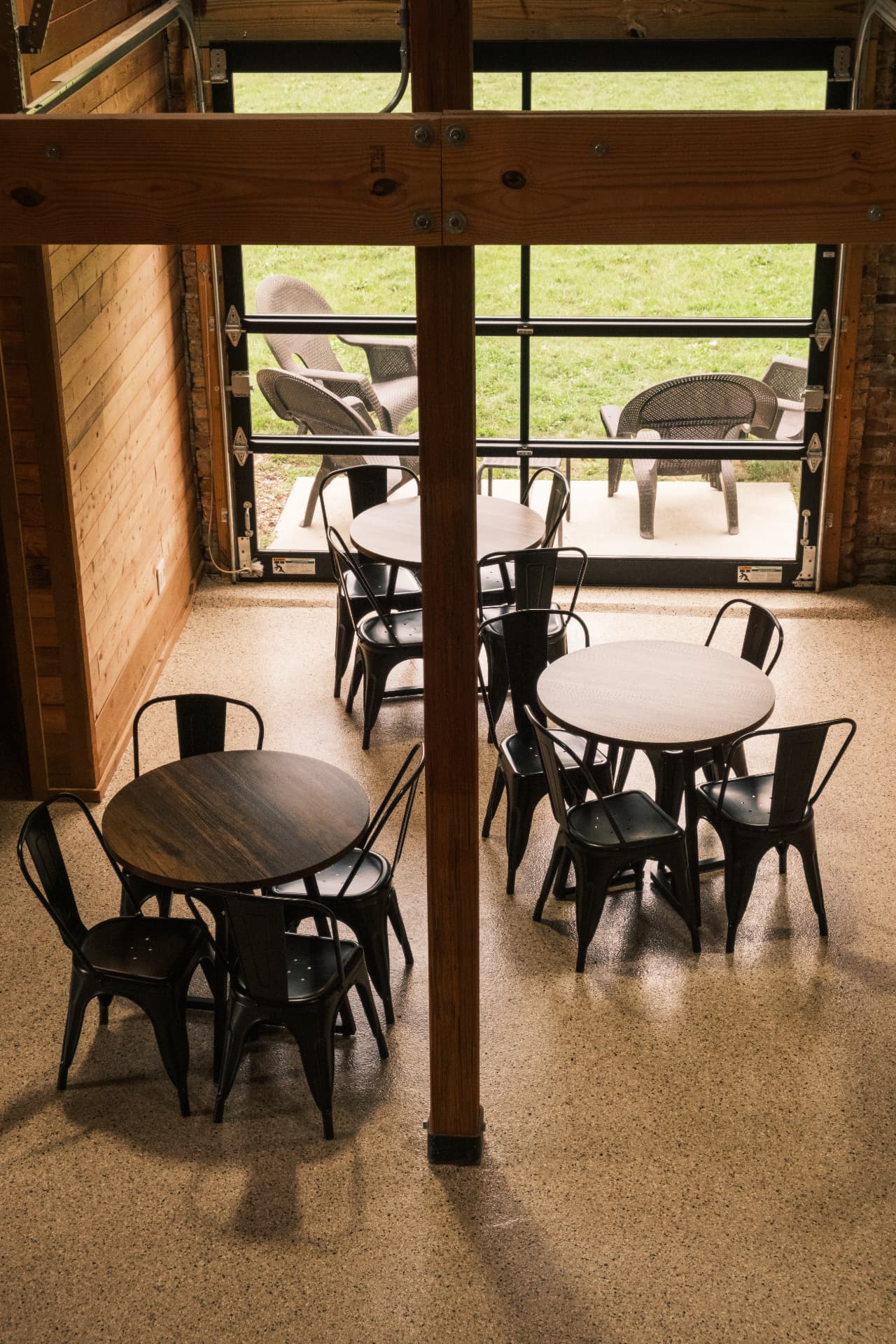 Tables and chairs inside DSCO Coffee facing the open garage door and patio