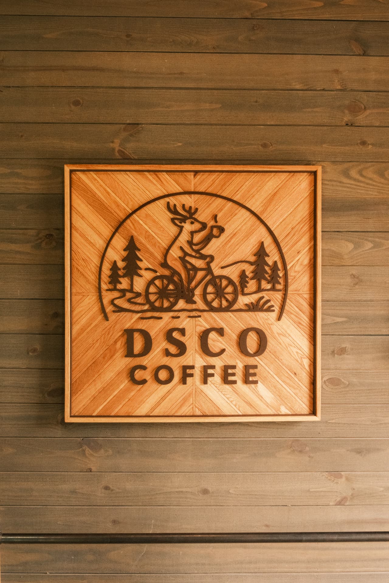 Handcrafted wooden DSCO Coffee sign with the deer riding a bicycle